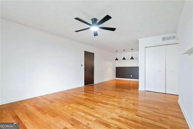 interior space with ceiling fan, a textured ceiling, and light wood-type flooring