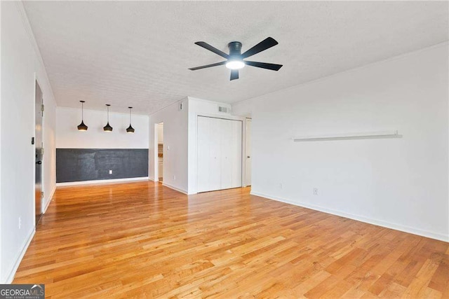 unfurnished living room with ceiling fan, a textured ceiling, and light wood-type flooring