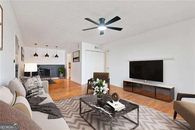 living room featuring ceiling fan, wood-type flooring, and a textured ceiling