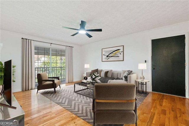 living room featuring ceiling fan, hardwood / wood-style floors, and a textured ceiling