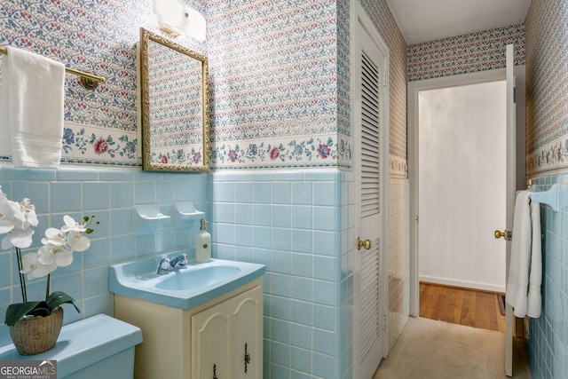 bathroom with vanity, toilet, and tile walls