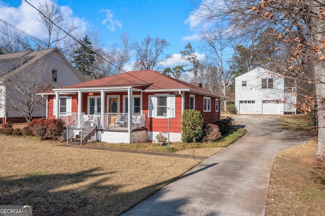 view of front facade with an outbuilding, a garage, covered porch, and a front yard