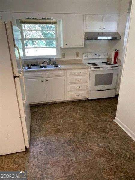 kitchen with white cabinetry, sink, extractor fan, and white appliances