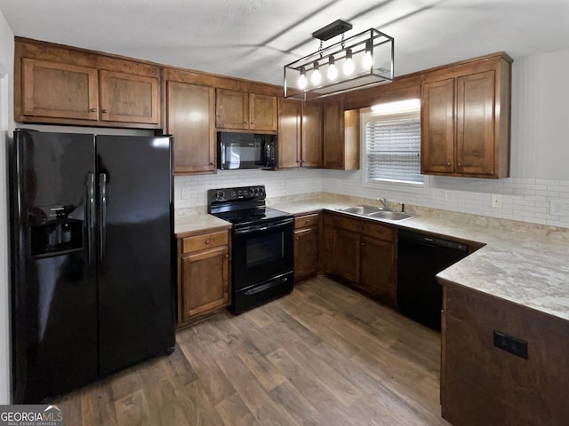 kitchen featuring sink, hanging light fixtures, tasteful backsplash, dark hardwood / wood-style floors, and black appliances