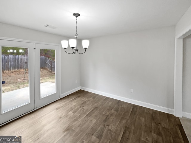 unfurnished dining area featuring hardwood / wood-style floors and a chandelier