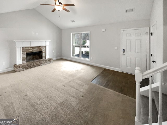 unfurnished living room featuring ceiling fan, wood-type flooring, lofted ceiling, and a brick fireplace