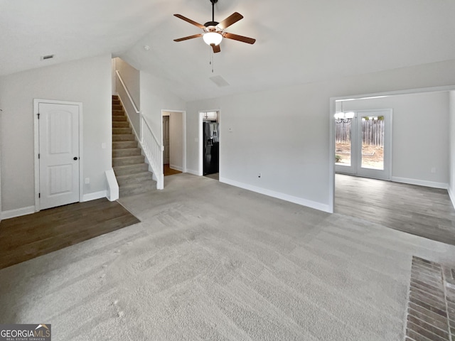 unfurnished living room featuring ceiling fan with notable chandelier, light colored carpet, and lofted ceiling