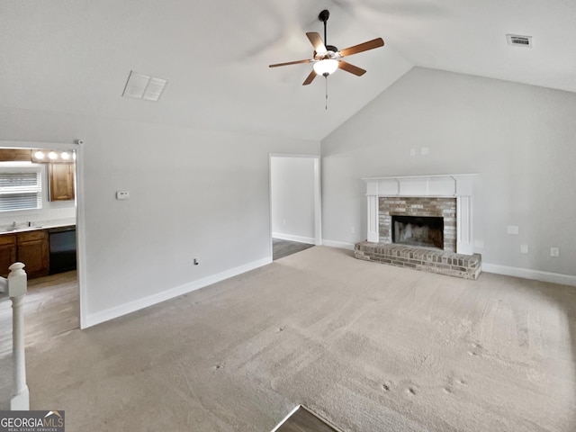 unfurnished living room with high vaulted ceiling, sink, ceiling fan, a fireplace, and carpet floors