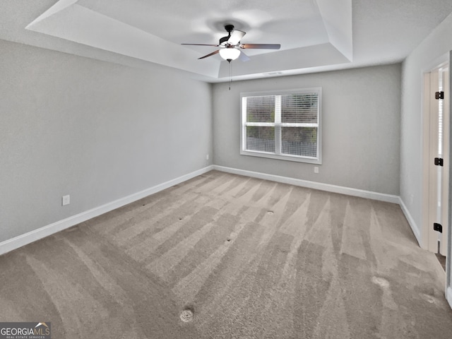 unfurnished room with light colored carpet, ceiling fan, and a tray ceiling