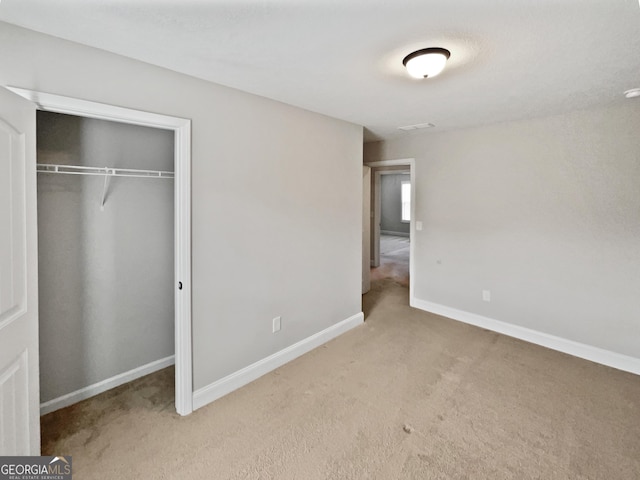 unfurnished bedroom with light carpet and a closet