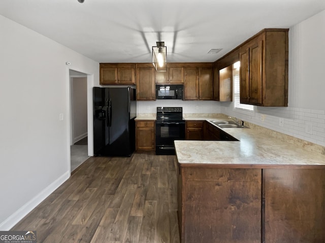 kitchen with sink, tasteful backsplash, dark hardwood / wood-style floors, kitchen peninsula, and black appliances