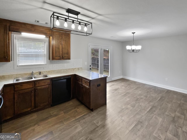 kitchen with kitchen peninsula, sink, wood-type flooring, decorative light fixtures, and dishwasher