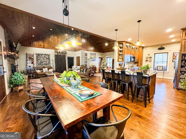 dining area with light hardwood / wood-style flooring, a healthy amount of sunlight, and vaulted ceiling