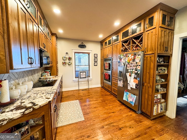 kitchen with backsplash, light stone counters, black appliances, and dark hardwood / wood-style floors