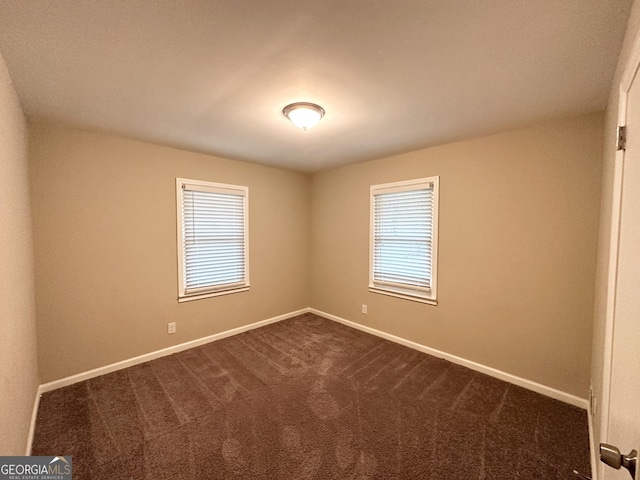 spare room featuring dark carpet