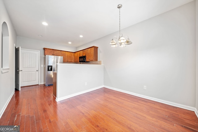 kitchen featuring stainless steel fridge, an inviting chandelier, hanging light fixtures, and hardwood / wood-style flooring