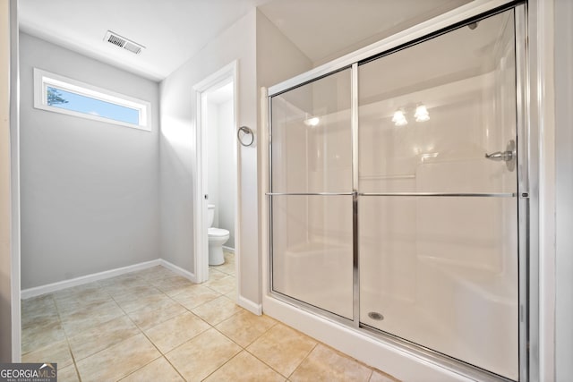 bathroom with tile patterned flooring, toilet, and an enclosed shower