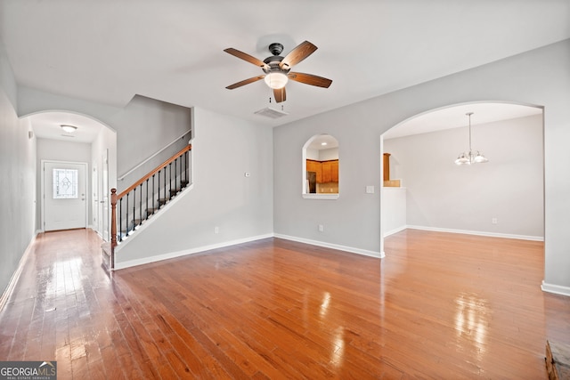 unfurnished living room featuring ceiling fan with notable chandelier and light hardwood / wood-style flooring