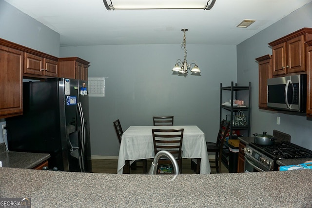 kitchen with pendant lighting, appliances with stainless steel finishes, and an inviting chandelier