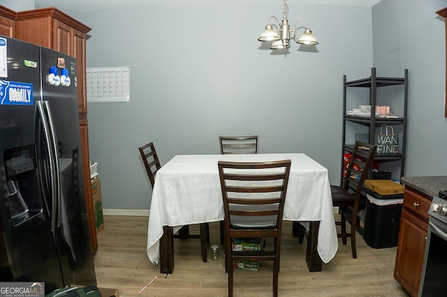 dining space with light hardwood / wood-style flooring and a chandelier