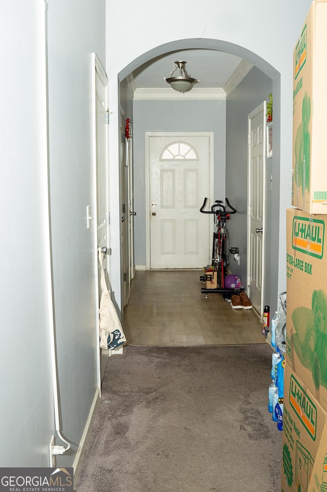 corridor featuring ornamental molding and dark colored carpet