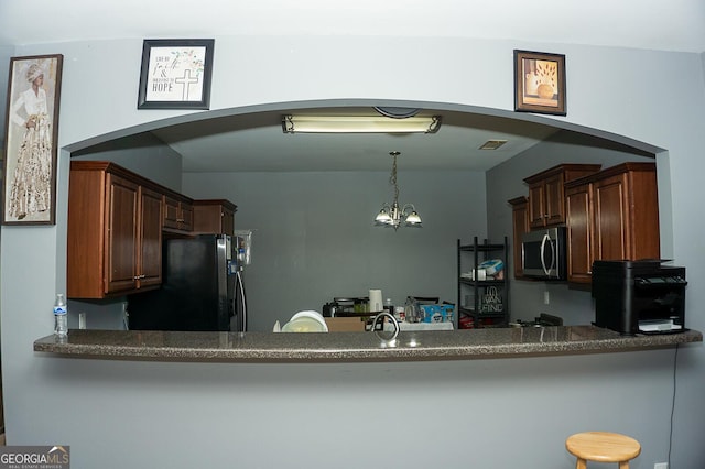 kitchen featuring pendant lighting, black refrigerator, sink, and an inviting chandelier