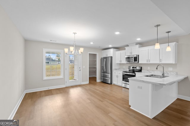 kitchen featuring white cabinets, sink, light hardwood / wood-style flooring, decorative light fixtures, and stainless steel appliances