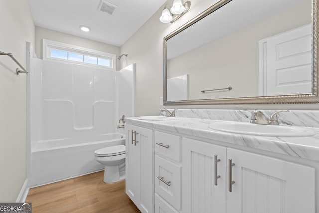 full bathroom featuring washtub / shower combination, vanity, hardwood / wood-style flooring, and toilet