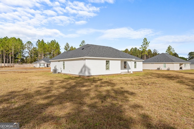 rear view of house with central AC and a yard