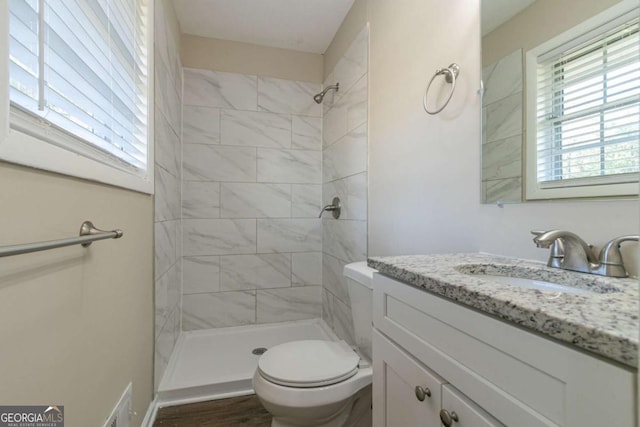 bathroom with vanity, toilet, wood-type flooring, and tiled shower