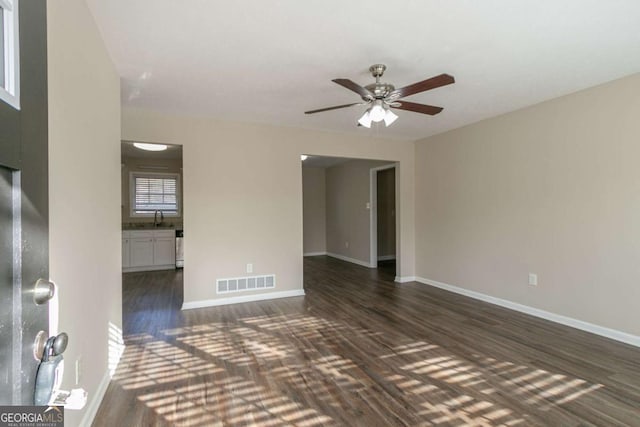 unfurnished room with ceiling fan, sink, and dark wood-type flooring