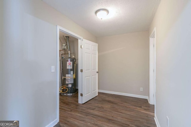 hallway featuring a textured ceiling, dark hardwood / wood-style flooring, and gas water heater