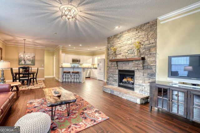 living room with a fireplace, a textured ceiling, crown molding, and dark wood-type flooring