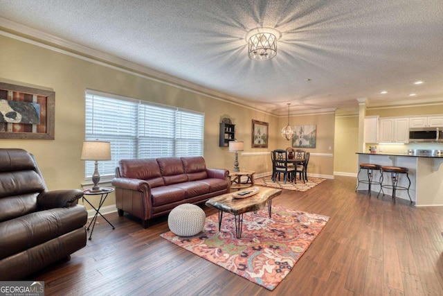 living room with crown molding, dark wood-type flooring, and a textured ceiling