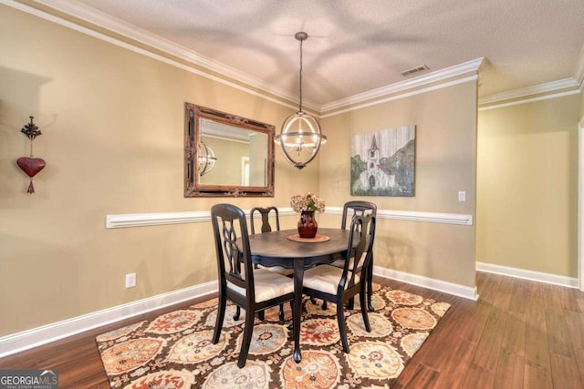 dining room featuring hardwood / wood-style floors, a chandelier, a textured ceiling, and ornamental molding