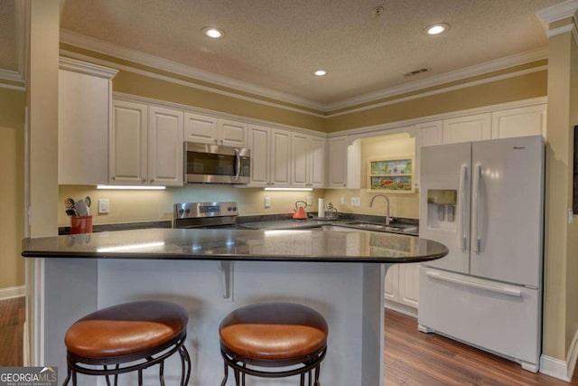 kitchen featuring sink, white cabinets, a textured ceiling, and appliances with stainless steel finishes