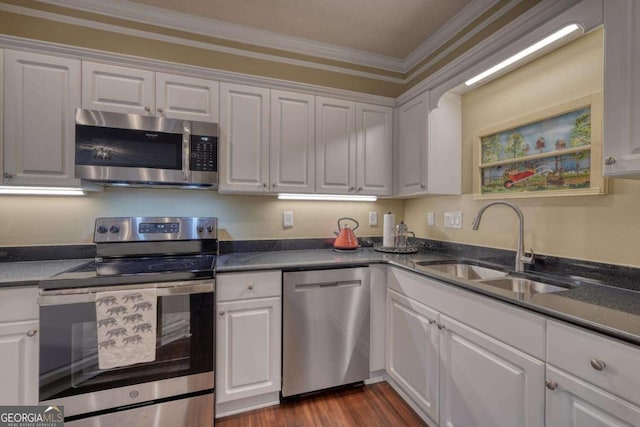 kitchen with dark wood-type flooring, white cabinets, sink, ornamental molding, and appliances with stainless steel finishes