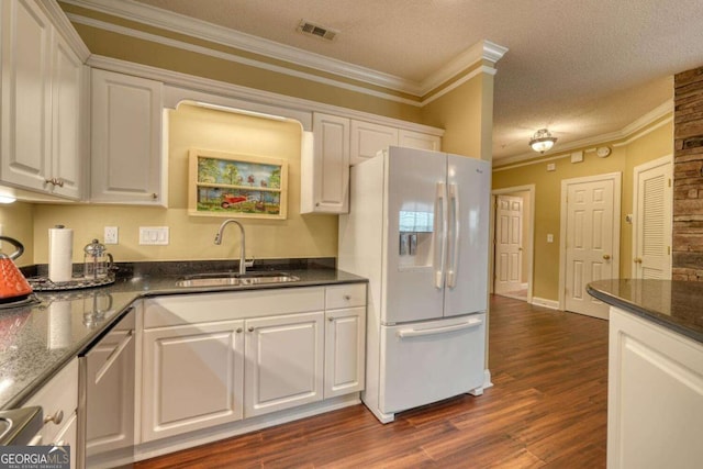 kitchen with white cabinets, white refrigerator with ice dispenser, sink, and a textured ceiling