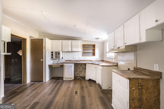 kitchen with lofted ceiling, dark wood-type flooring, sink, ornamental molding, and white cabinetry