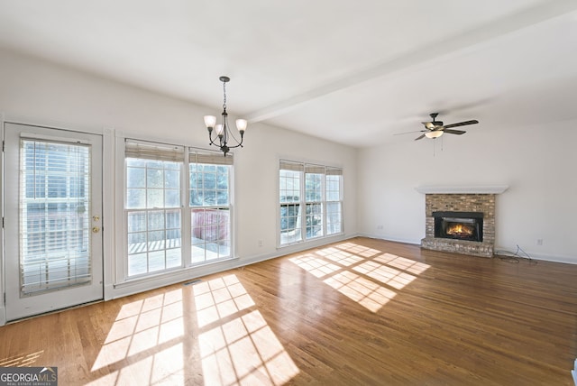 unfurnished living room with ceiling fan with notable chandelier, hardwood / wood-style flooring, beamed ceiling, and a fireplace