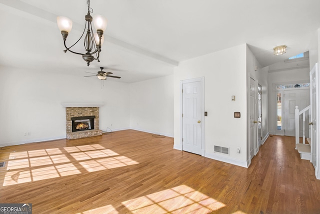 unfurnished living room with ceiling fan with notable chandelier, a fireplace, lofted ceiling, and hardwood / wood-style floors