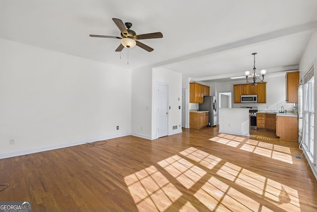 unfurnished living room featuring ceiling fan with notable chandelier, light hardwood / wood-style floors, and sink