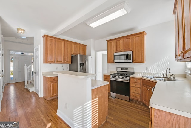 kitchen with sink, appliances with stainless steel finishes, a center island, light wood-type flooring, and beam ceiling