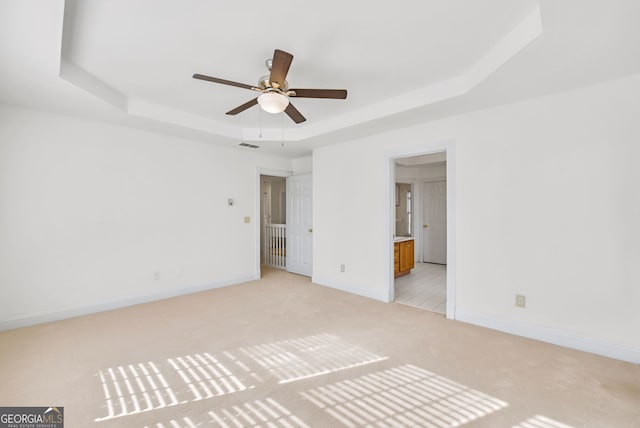 carpeted spare room featuring a raised ceiling and ceiling fan