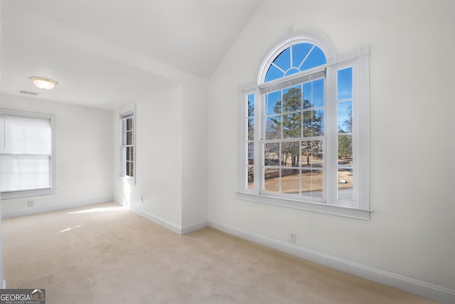 spare room featuring light carpet and lofted ceiling