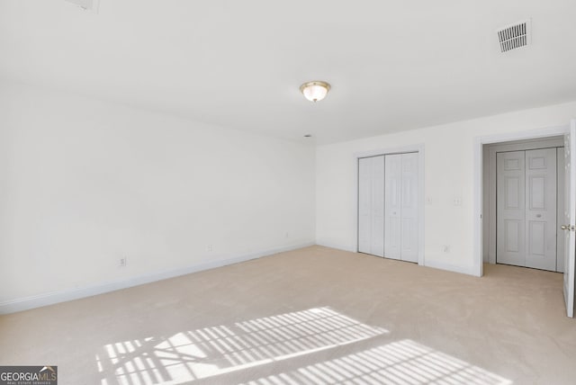 unfurnished bedroom featuring a closet and light colored carpet