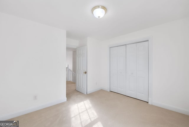 unfurnished bedroom with light colored carpet and a closet