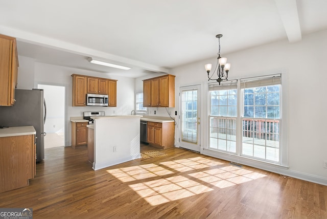 kitchen with light hardwood / wood-style floors, stainless steel appliances, a notable chandelier, a kitchen island, and beam ceiling