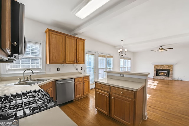 kitchen with appliances with stainless steel finishes, beamed ceiling, dark hardwood / wood-style flooring, a brick fireplace, and decorative light fixtures