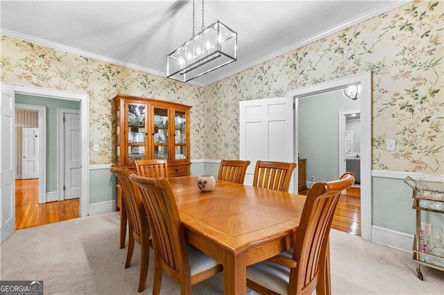 dining area with crown molding, a notable chandelier, and light wood-type flooring